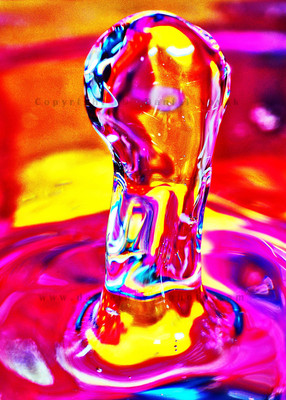 A droplet of water bouncing up against a vividly colorful background.