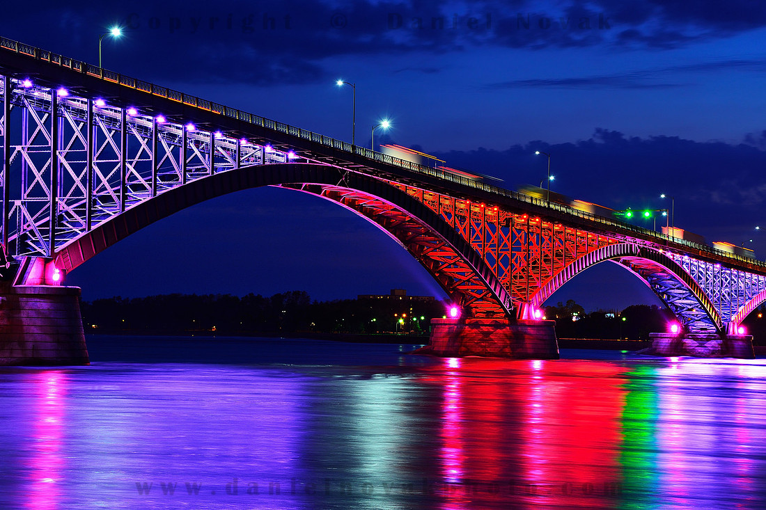 Alternating vVolet and Red Peace Bridge at Dusk with Reflections in the Niagara River, Buffalo, New York (NY).