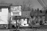 Graffiti Grafix Signs, an old business in Orchard Park, NY. An old-fashioned black and white analog photograph captured with a 35mm Pentax Spotmatic camera on Kodak T-Max 100 negative film.